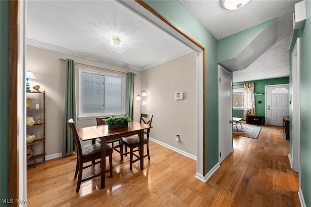 dining room featuring ornamental molding, light wood finished floors, and baseboards