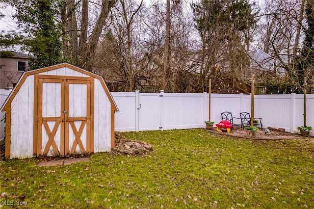 view of yard with a gate, a fenced backyard, an outdoor structure, and a storage unit