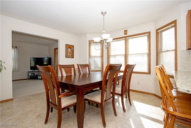 dining area with light tile patterned floors, baseboards, and an inviting chandelier