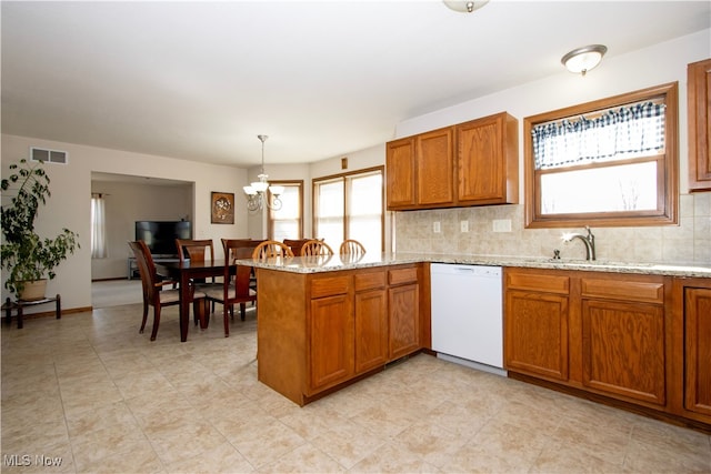 kitchen with white dishwasher, a peninsula, a sink, visible vents, and brown cabinets