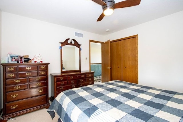 bedroom with a ceiling fan, a closet, visible vents, and light carpet