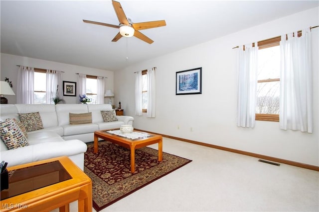 living room with carpet floors, visible vents, baseboards, and a ceiling fan