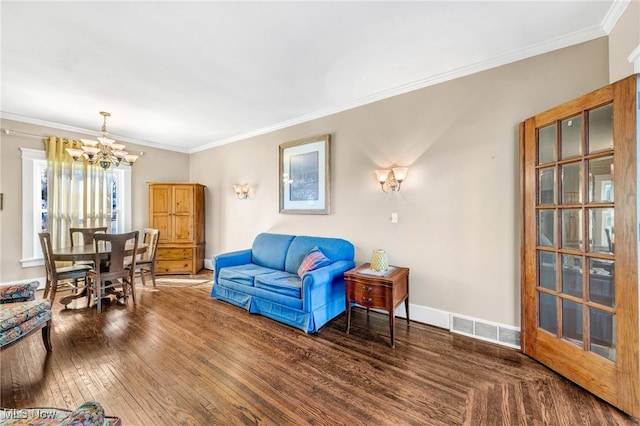 living area with visible vents, baseboards, hardwood / wood-style floors, crown molding, and a notable chandelier