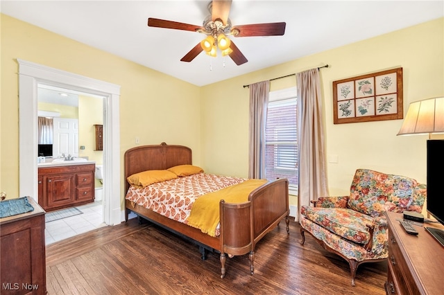 bedroom featuring connected bathroom, a sink, ceiling fan, and wood finished floors