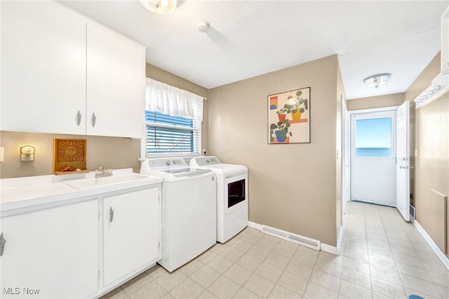 laundry area featuring washing machine and dryer, a sink, cabinet space, and baseboards