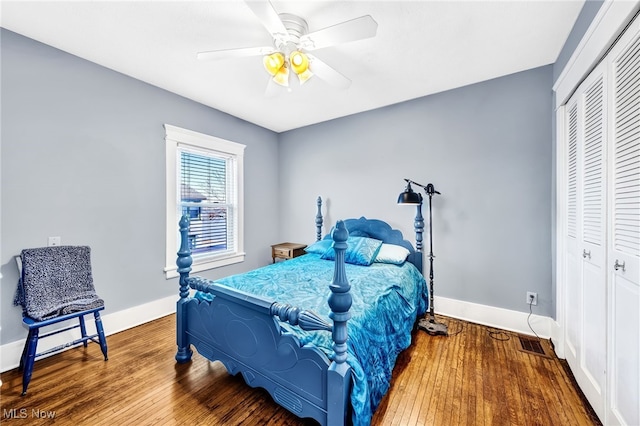 bedroom with a closet, visible vents, baseboards, and wood finished floors