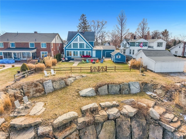 view of yard featuring a deck, an outdoor fire pit, a fenced backyard, an outdoor structure, and a residential view