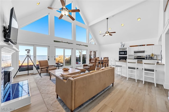 living area with high vaulted ceiling, light wood-style floors, a ceiling fan, and beamed ceiling