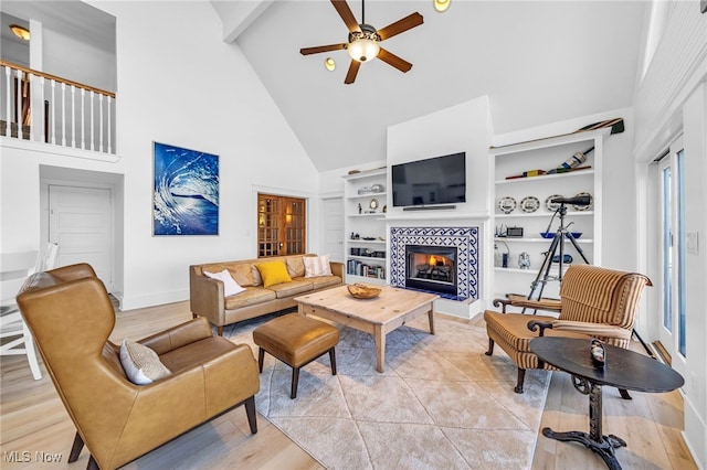 living room featuring a tile fireplace, a ceiling fan, baseboards, built in features, and beamed ceiling