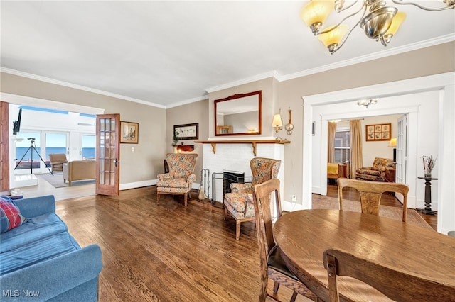 living room with baseboards, a fireplace, wood finished floors, and crown molding