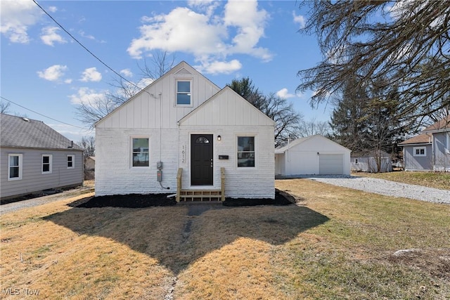 bungalow-style home featuring an outbuilding, a garage, driveway, a front lawn, and board and batten siding