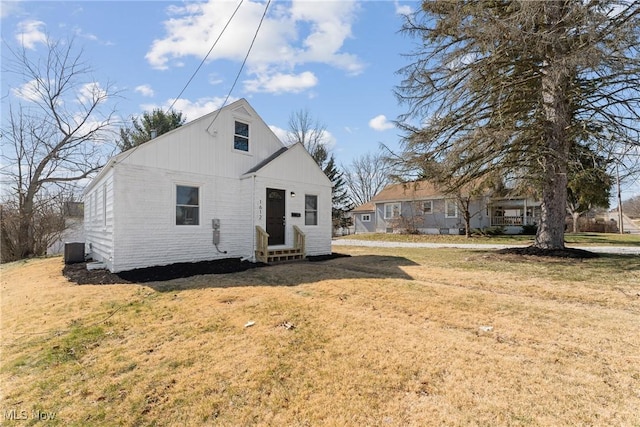 rear view of house with entry steps, a lawn, and central AC unit