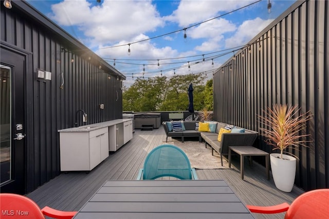 wooden terrace with an outdoor living space, a sink, and outdoor dining space