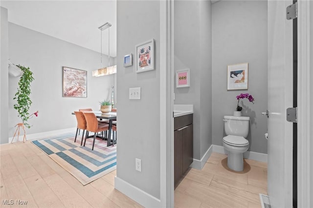 bathroom with toilet, vanity, wood finished floors, and visible vents