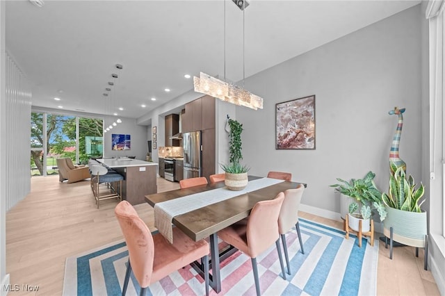 dining space with a wall of windows, light wood-type flooring, baseboards, and recessed lighting