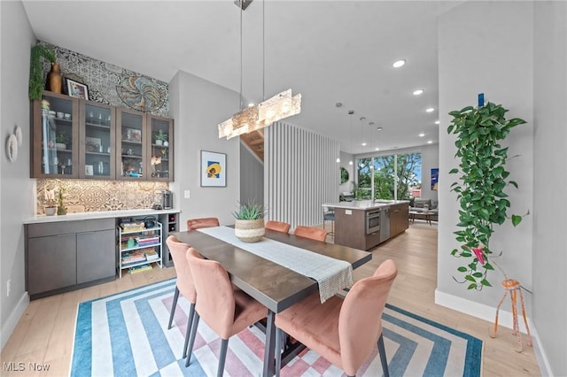 dining space featuring baseboards, a dry bar, light wood-style flooring, and recessed lighting