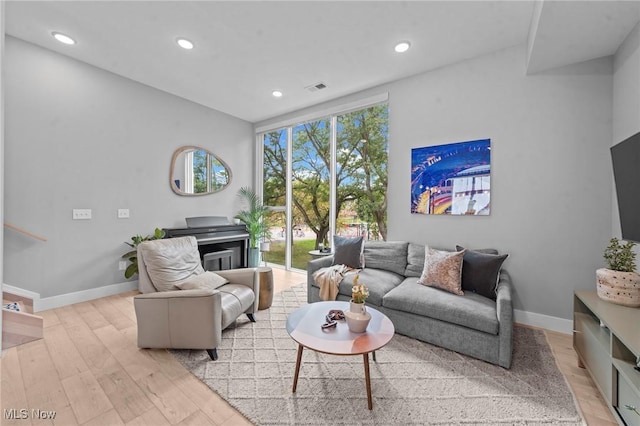 living area with light wood-style flooring, visible vents, baseboards, and recessed lighting