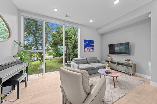 living room featuring light wood-type flooring, visible vents, baseboards, and recessed lighting