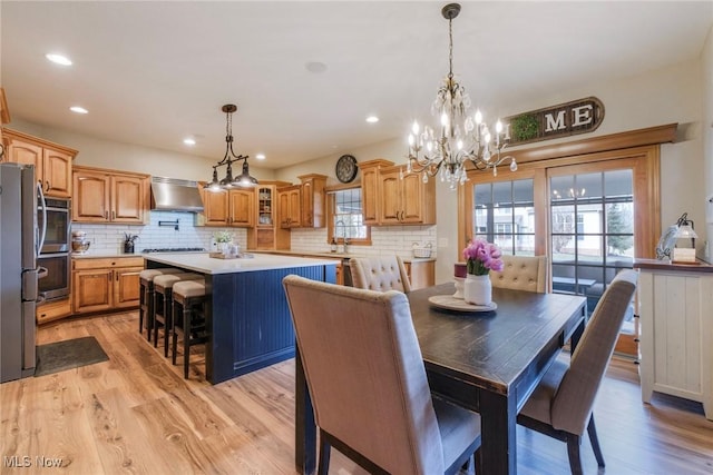 dining area with light wood-style floors, a notable chandelier, and recessed lighting