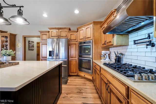 kitchen featuring under cabinet range hood, stainless steel appliances, light wood-style floors, hanging light fixtures, and backsplash