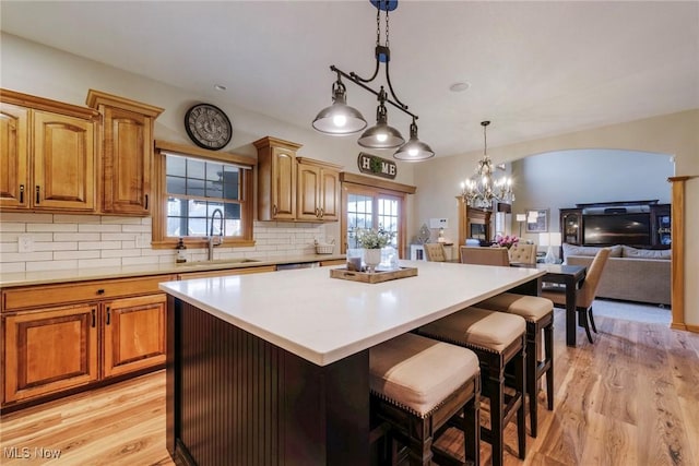 kitchen with a kitchen island, light wood-type flooring, a sink, and tasteful backsplash