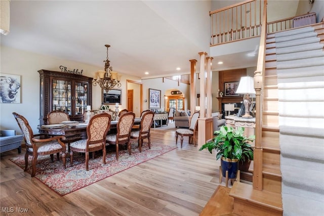 dining space with recessed lighting, light wood-type flooring, decorative columns, and a notable chandelier