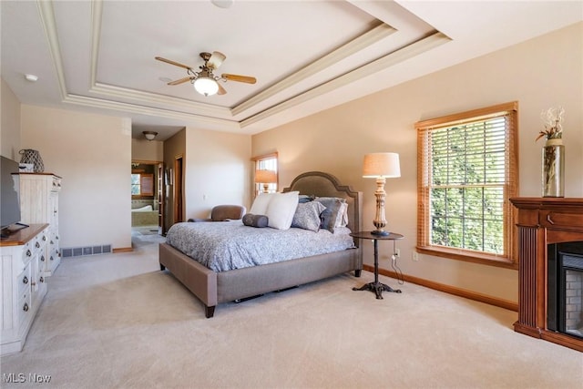 bedroom featuring light colored carpet, a fireplace, visible vents, baseboards, and a raised ceiling