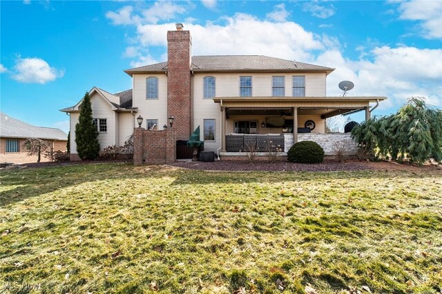 back of property with a yard, a chimney, and a patio