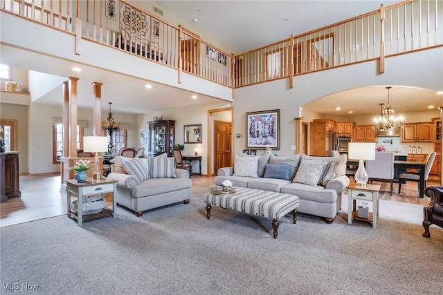 living area featuring an inviting chandelier, visible vents, arched walkways, and recessed lighting