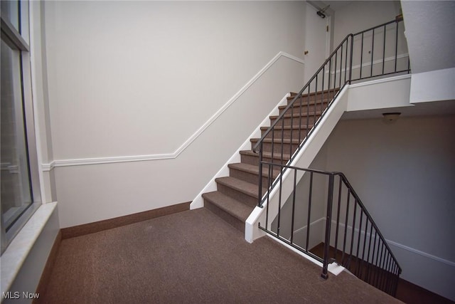 stairway with a high ceiling, carpet flooring, and baseboards