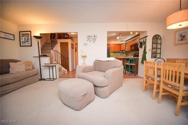 living room featuring light carpet and stairway