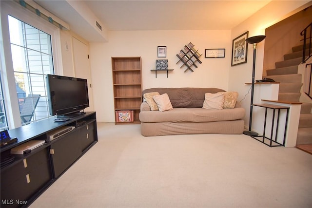 living area with carpet floors, stairs, and visible vents