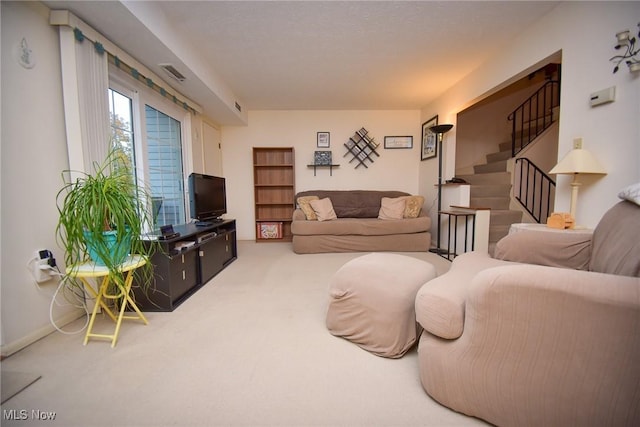 living room with carpet floors, visible vents, and stairs