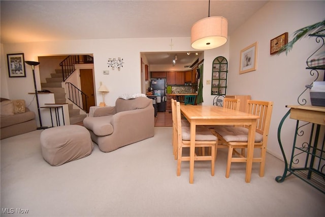 dining space with stairs and light colored carpet