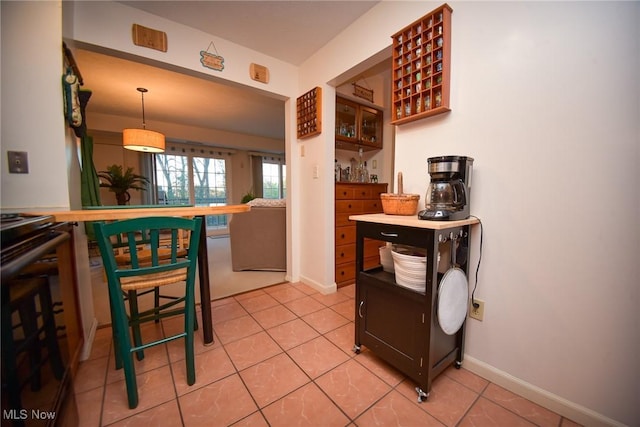 kitchen with hanging light fixtures, electric range, baseboards, and light tile patterned flooring