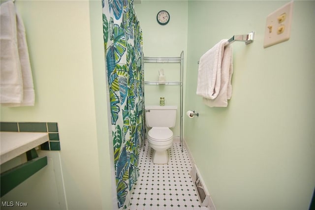 full bath featuring toilet, a shower with curtain, visible vents, and baseboards