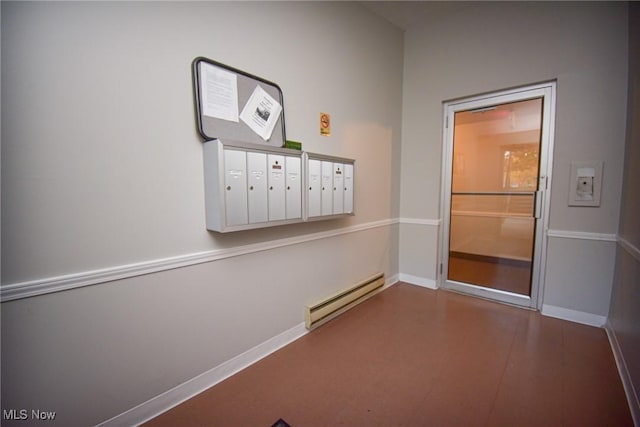 hall featuring a baseboard heating unit, baseboards, mail area, and wood finished floors