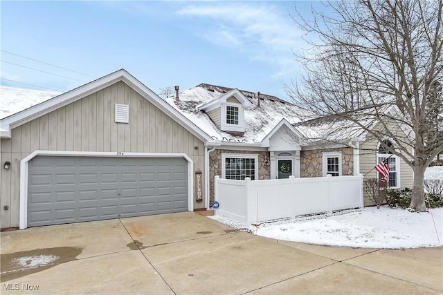 view of front of house with a fenced front yard, stone siding, driveway, and a garage