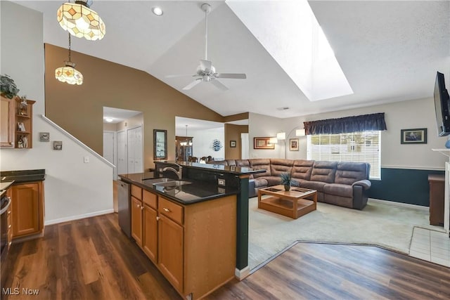 kitchen featuring vaulted ceiling with skylight, dark wood finished floors, dishwasher, open floor plan, and a sink