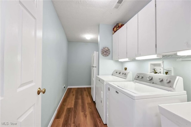 washroom with cabinet space, visible vents, dark wood finished floors, washer and clothes dryer, and a sink