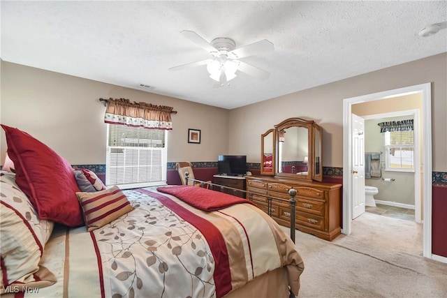 carpeted bedroom featuring ensuite bath, ceiling fan, visible vents, and a textured ceiling