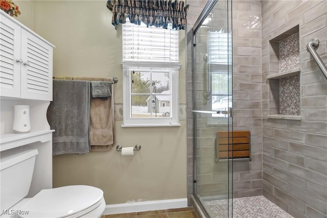 full bathroom with toilet, a stall shower, and baseboards