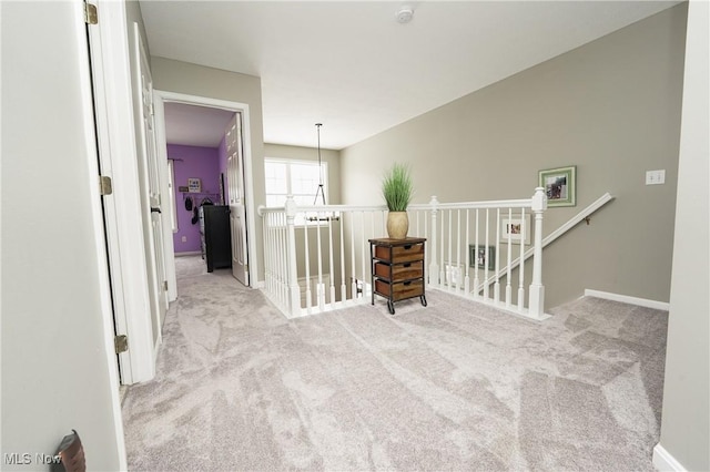 hallway with carpet, baseboards, and an upstairs landing