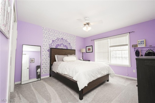 carpeted bedroom with wallpapered walls, ceiling fan, an accent wall, and baseboards