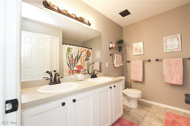 full bathroom with double vanity, a sink, toilet, and baseboards