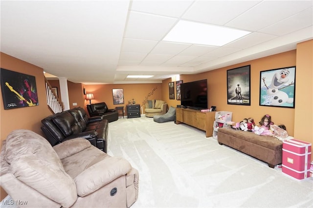 living area featuring stairs, a drop ceiling, and carpet flooring