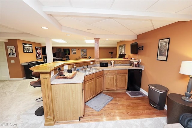 bar featuring a paneled ceiling, a sink, baseboards, fridge, and decorative columns