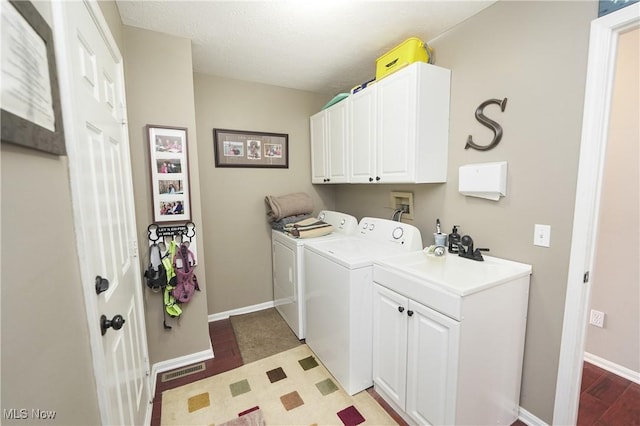 washroom featuring baseboards, visible vents, cabinet space, and washer and dryer