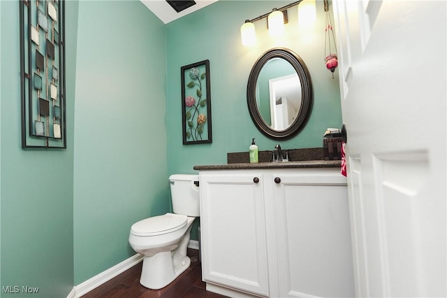 bathroom with toilet, baseboards, wood finished floors, and vanity