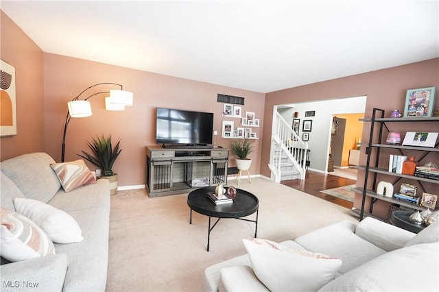 carpeted living room featuring visible vents, stairs, and baseboards